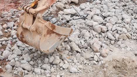 close-up of an excavator bucket digging into a pile of rocks