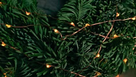 close up moving in towards a christmas wreath with fairy lights on a bed of cloth and transparent material