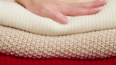 woman's hand arranging stacked knitted sweaters
