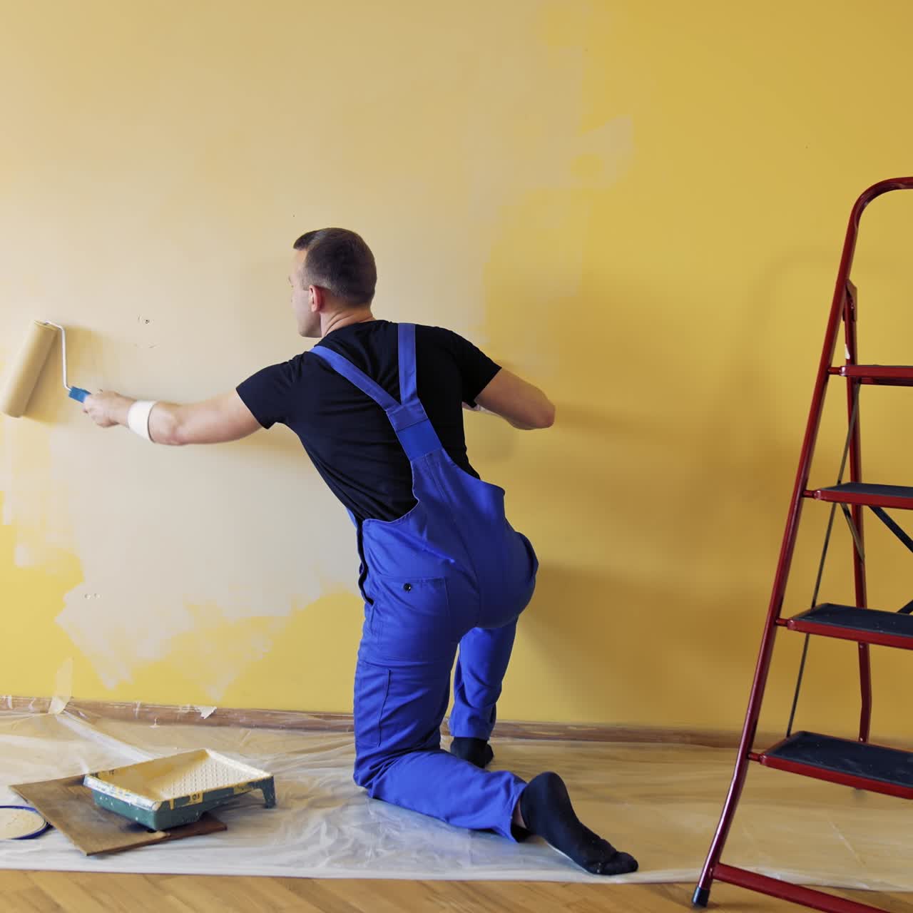 Young worker painting wall in room. Repair, building and home concept
