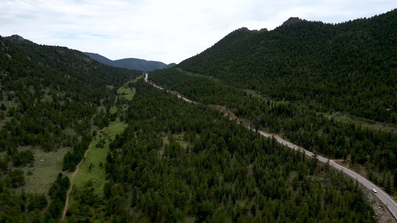 vista panorámica de árboles de bosque caducifolio y montañas con camino rural cerca de estes park, colorado