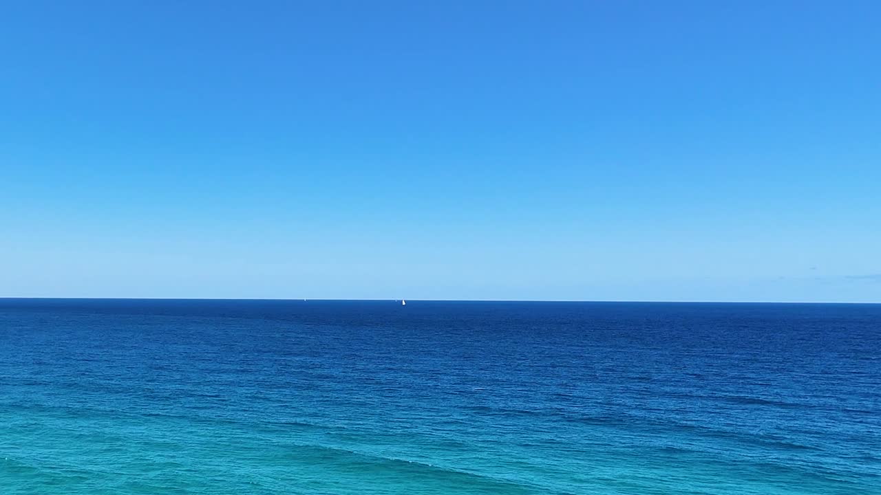 바다의 파도와 은 파란 하늘 아래의 해안선