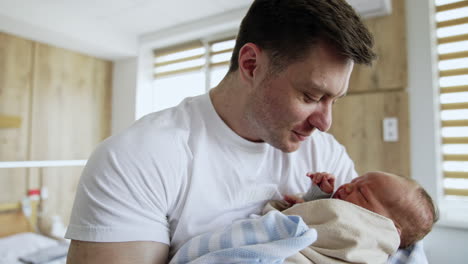 caring man tries to calm down his crying infant baby. father kisses his child and waves in hands.