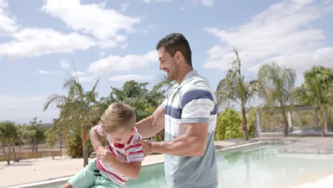 Glücklicher-Kaukasischer-Vater-Und-Sohn,-Die-Im-Schwimmbad-Des-Strandhauses-Spielen