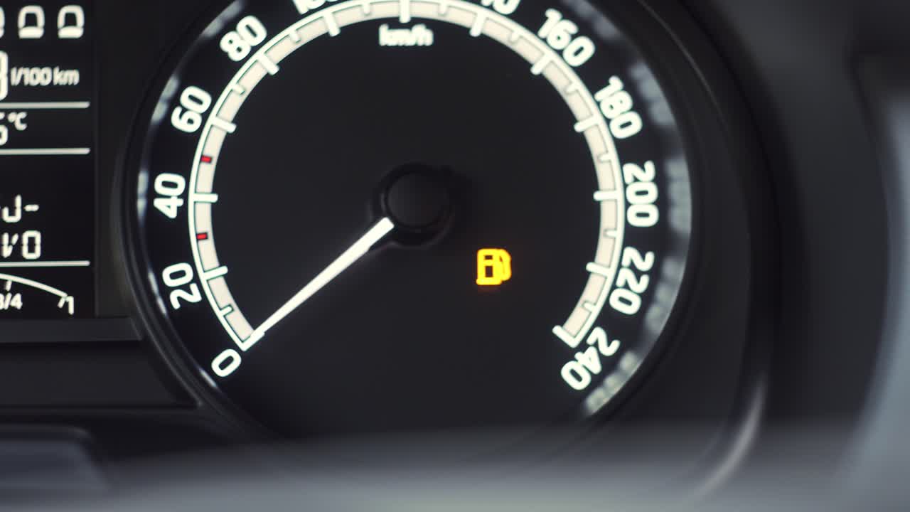 Car dashboard with low fuel indicator warning light showing off, extreme closeup