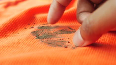 finger cleaning dirt from orange shirt