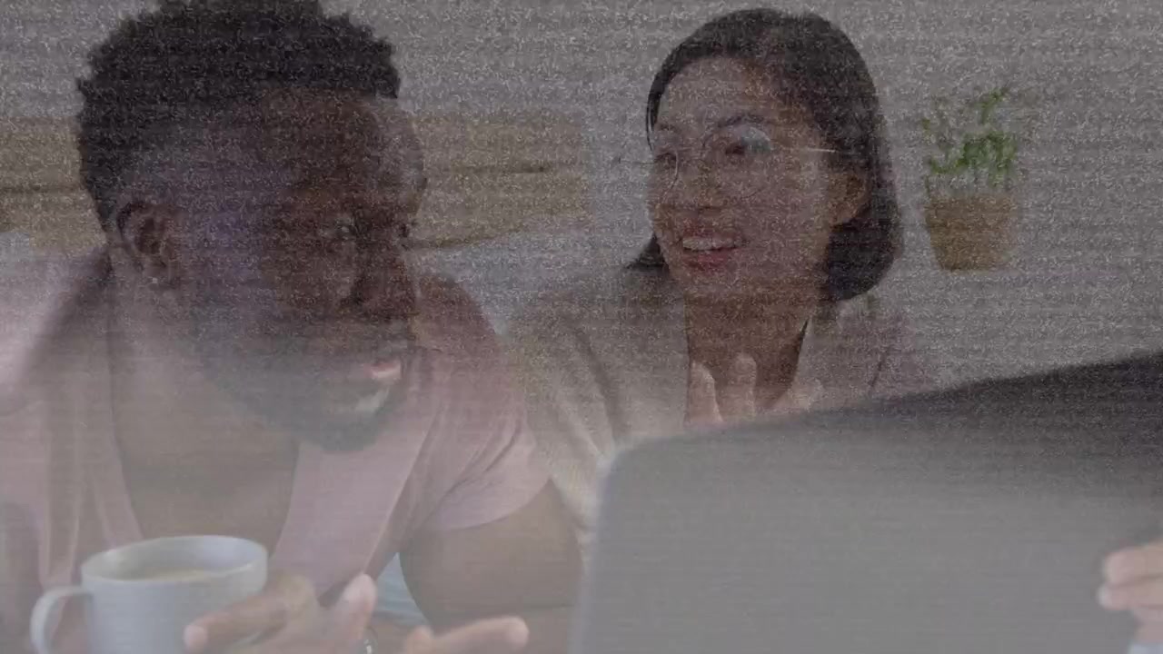 Happy Diverse Couple Talking and Smiling While Using Laptop at Home