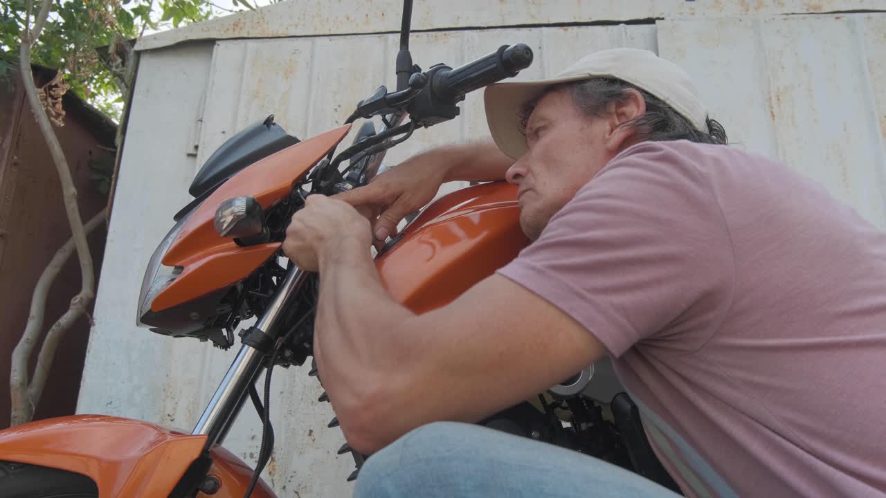 A man tightens a bolt on his motorcycle using a wrench