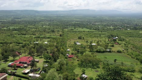 Eine-Drohnenaufnahme-Von-Ländlichen-Ackerflächen-In-Kenia-Mit-Grünen-Landschaften-Und-Einer-Hügelkette-Im-Hintergrund