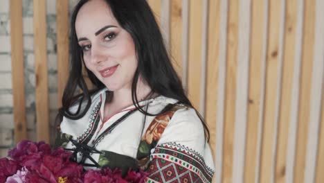 portrait features a beautiful young woman holding a bouquet of beautiful flowers, dressed in an embroidered authentic ukrainian shirt