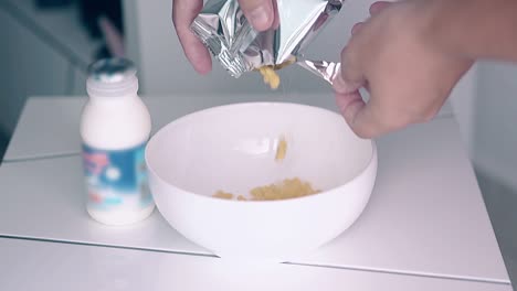 man-pours-flakes-from-silver-package-into-white-ceramic-bowl