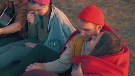 guy-and-girl-wrapped-in-plaid-with-friends-in-tourist-camp