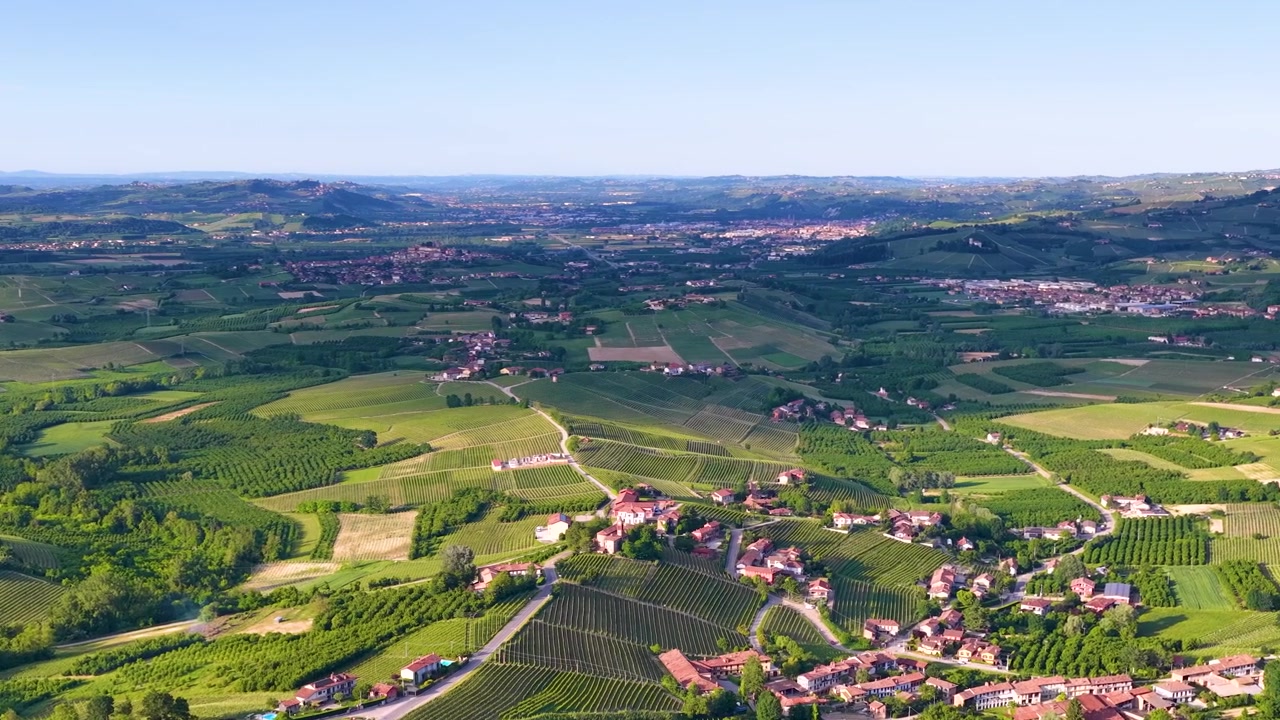 Breed luchtshot met drone panneert over weelderige groene wijngaarden en glooiende heuvels op het platteland van Italië.