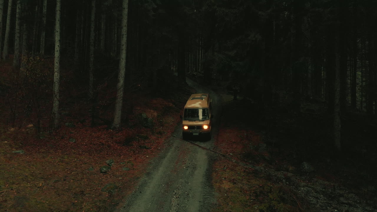Van driving through a dark autumn forest