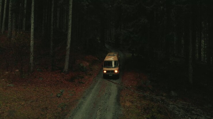 Van driving through a dark autumn forest