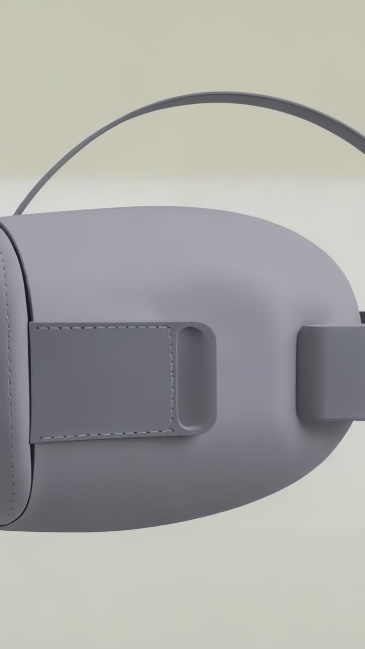 Vertical video: Orbiting camera circling matte gray VR headset in studio, revealing strap details