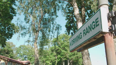 a golf sign pointing in the direction towards the driving range