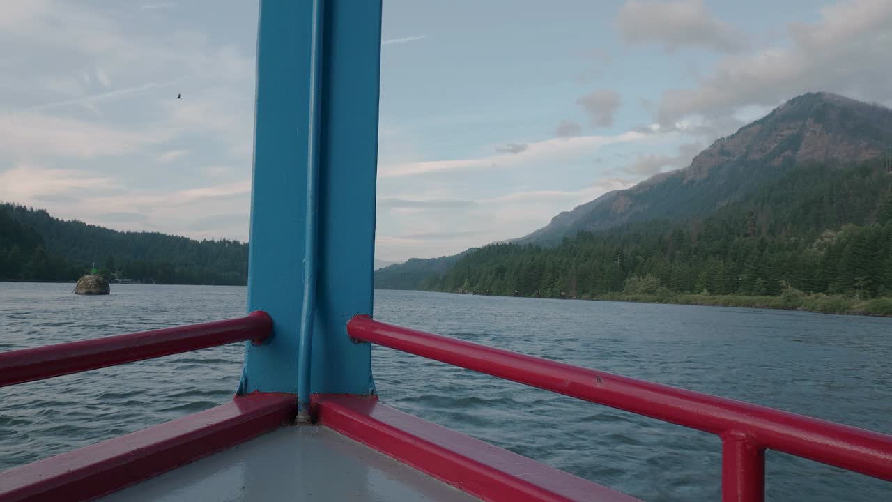 Cruise ship floating on Columbia River Gorge in Pacific Northwest Oregon with mountain scenery on a beautiful day slow motion