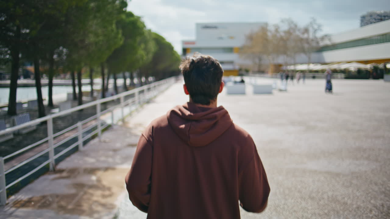 Urban runner training rear view. Closeup motivated man jogging sunny street