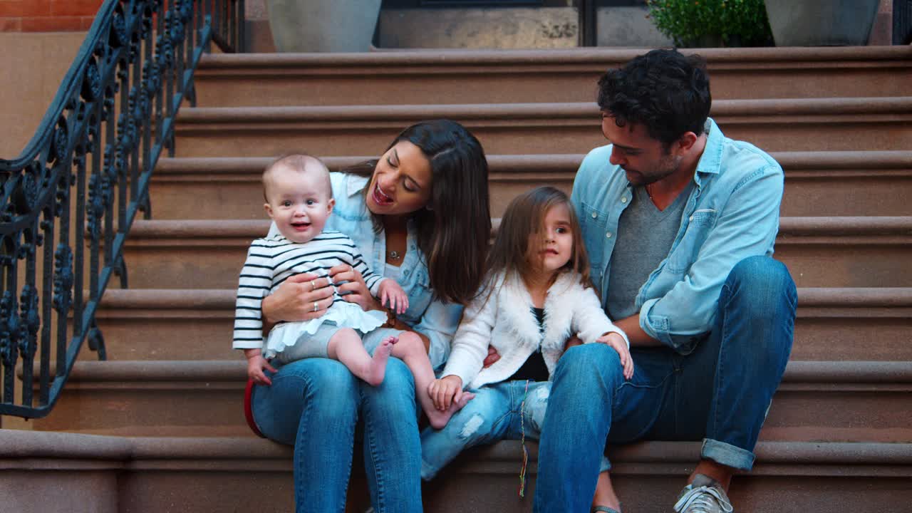 Young family with two kids sitting on front stoop, Brooklyn