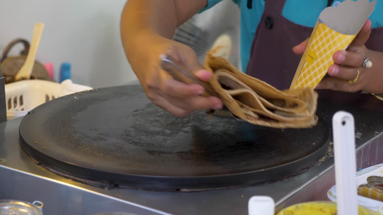 el chef terminó de cocinar un panqueque y lo dobla para colocarlo en el soporte