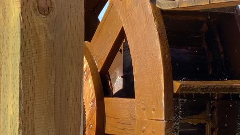 wooden wheel of watermill turns around, water splashing on paddles close up