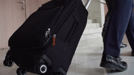 bottom view of a businessman carrying a suitcase, while walking with a colleague to the airport hotel reception