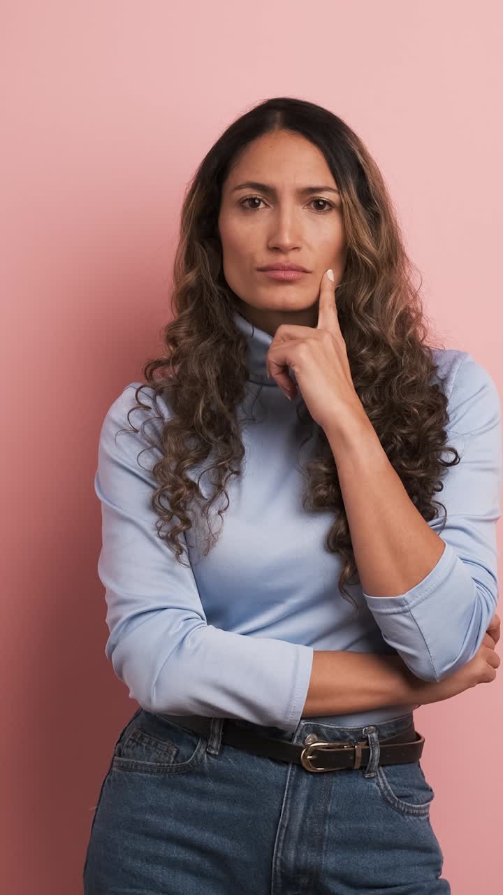 Hispanic woman looking around with thoughtful expression. Vertical footage