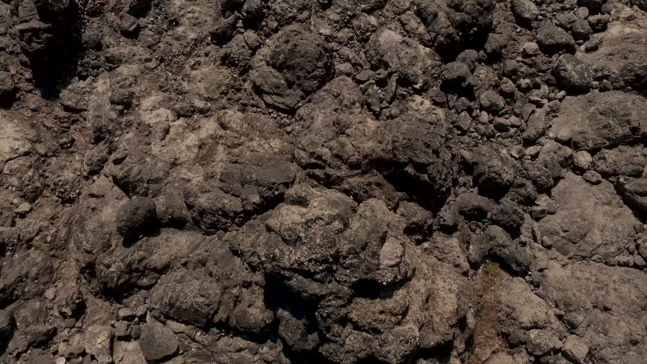 volando sobre la playa escarpada húmeda hacia el mar con reflejos solares en costa rica