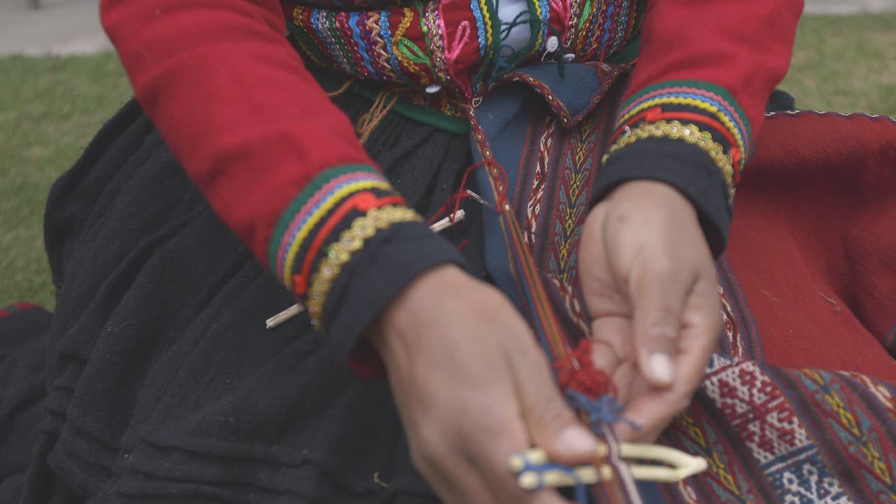 Peruvian weaver in full beautiful dress works on a weaving