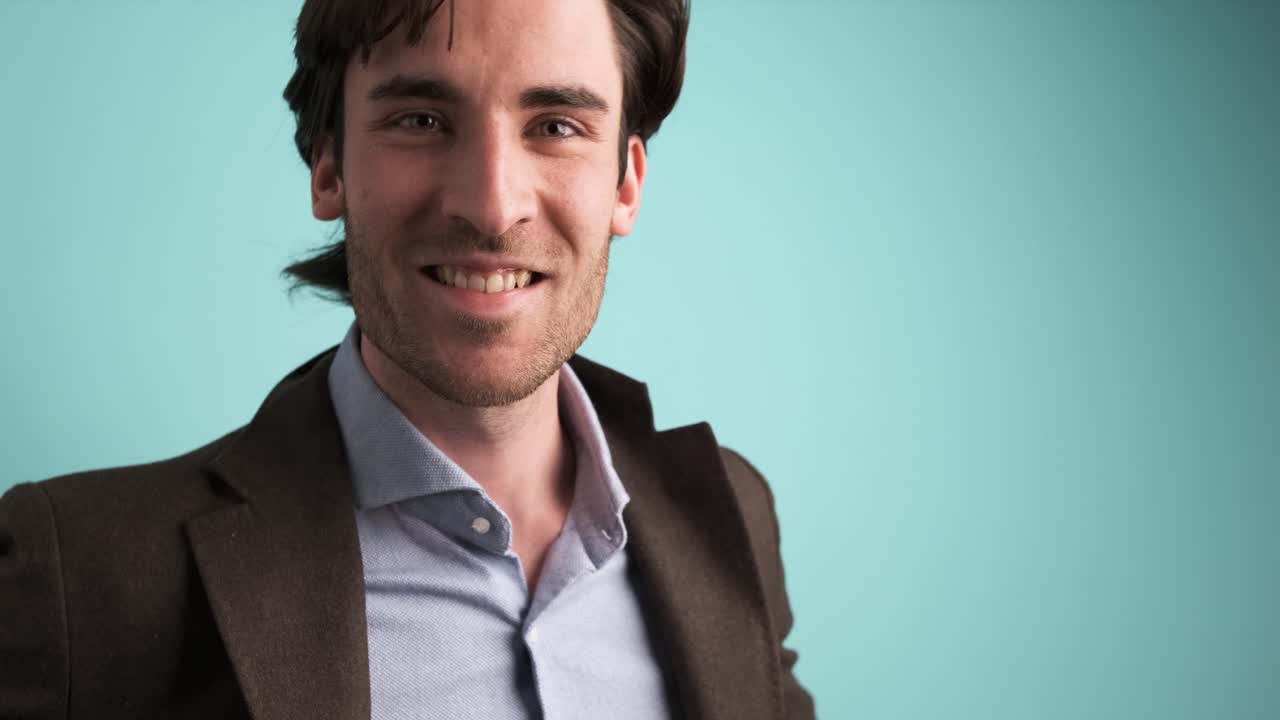 Smiling man in jacket looking at camera in blue studio