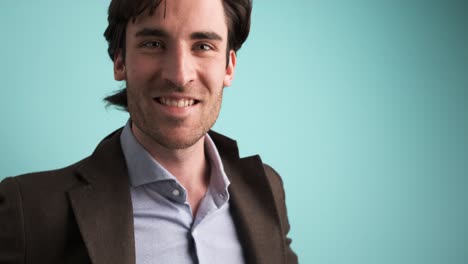 smiling man in jacket looking at camera in blue studio