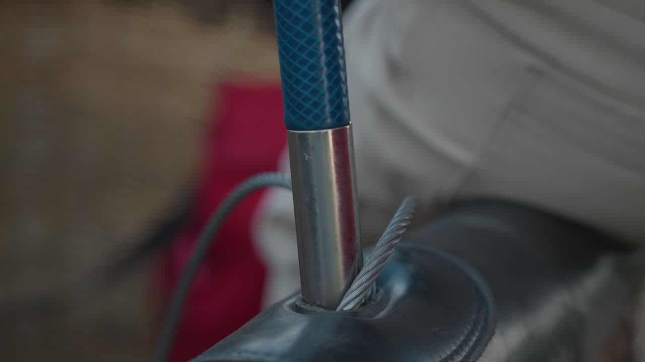 close up of ferrule and braided rope secured into basket rim with blurred form of seat and wicker backdrop hinting preflight balloon setup on rural roadside under overcast sky