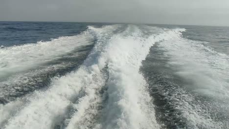 wake of water seen from behind of fast moving motor boat in a clear sky day,blue sea , water surface