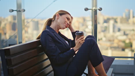 smiling woman sipping coffee on office balcony. happy manager resting alone