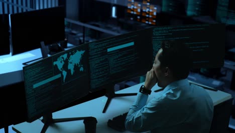 side view of tired asian man developer yawning before sleeping while write code with multiple computer screens in the office