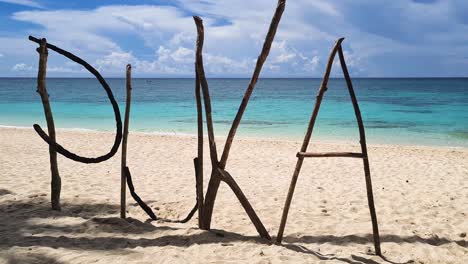 puka shell beach sign made from tree branches on white sand, boracay island, philippines, close up