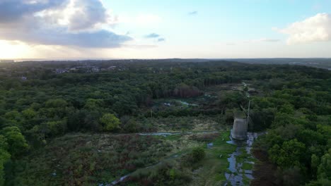 Bidston-Windmill-at-dawn,-aerial-drone-anti-clockwise-far-pan-Liverpool-sunrise-and-storm-clouds-reveal