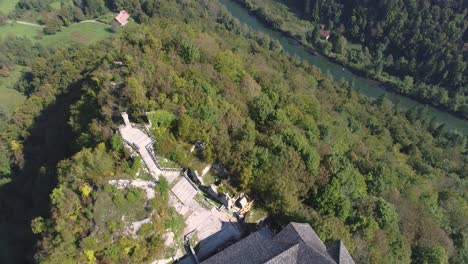 Antena-De-Alto-ángulo-Que-Revela-El-Castillo-De-Kostel-En-Una-Colina-Junto-Al-Río-Kolpa,-Eslovenia