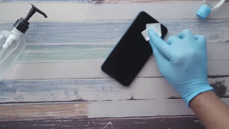 cleaning a smartphone with protective gloves and sanitizer