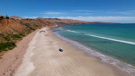 Una-Vista-De-Drone-De-Una-Autocaravana-Conduciendo-Por-Una-Hermosa-Playa-De-Arena-Blanca-En-El-Sur-De-Australia