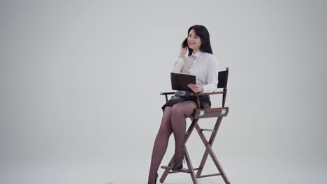 portrait of a beautiful businesswoman with a phone. young woman sitting in the chair with a black folder and talking the mobile phone indoors.