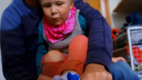 father helping his son to wear socks in bedroom at home 4k