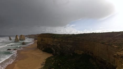 waves crash against cliffs under dark clouds