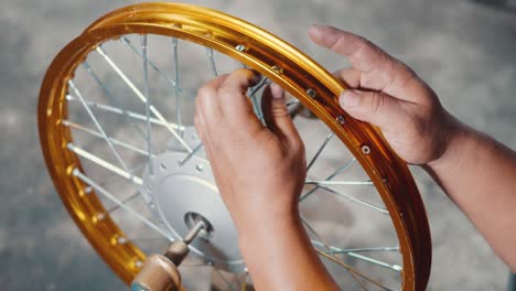 técnico hombre trabajando rueda de motocicleta tiene rayos tejer en herramienta mecánica nueva rueda de acero