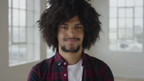 portrait of young mixed race student man smiling happy looking at camera enjoying independent lifestyle in apartment trendy afro hairstyle slow motion