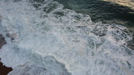 Aerial-Overhead-View-Of-Nazare-Beach-Waves-Breaking-With-White-Foam-Along-Coastline