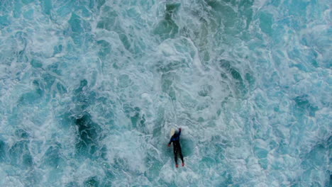 Antena:-Vista-De-Pájaro-Del-Surfista-Luchando-Contra-Las-Olas,-Corriente-Y-Lavado-Blanco-En-Un-Océano-Turbulento