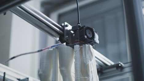 a 3d printer extruding white filament to create objects