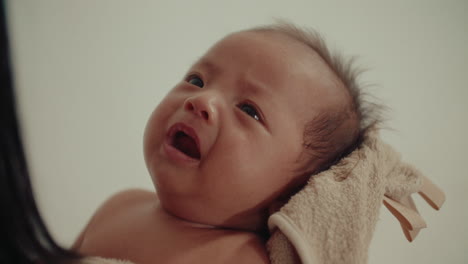 mother holding and cuddling a newborn baby in blanket after taking bath
